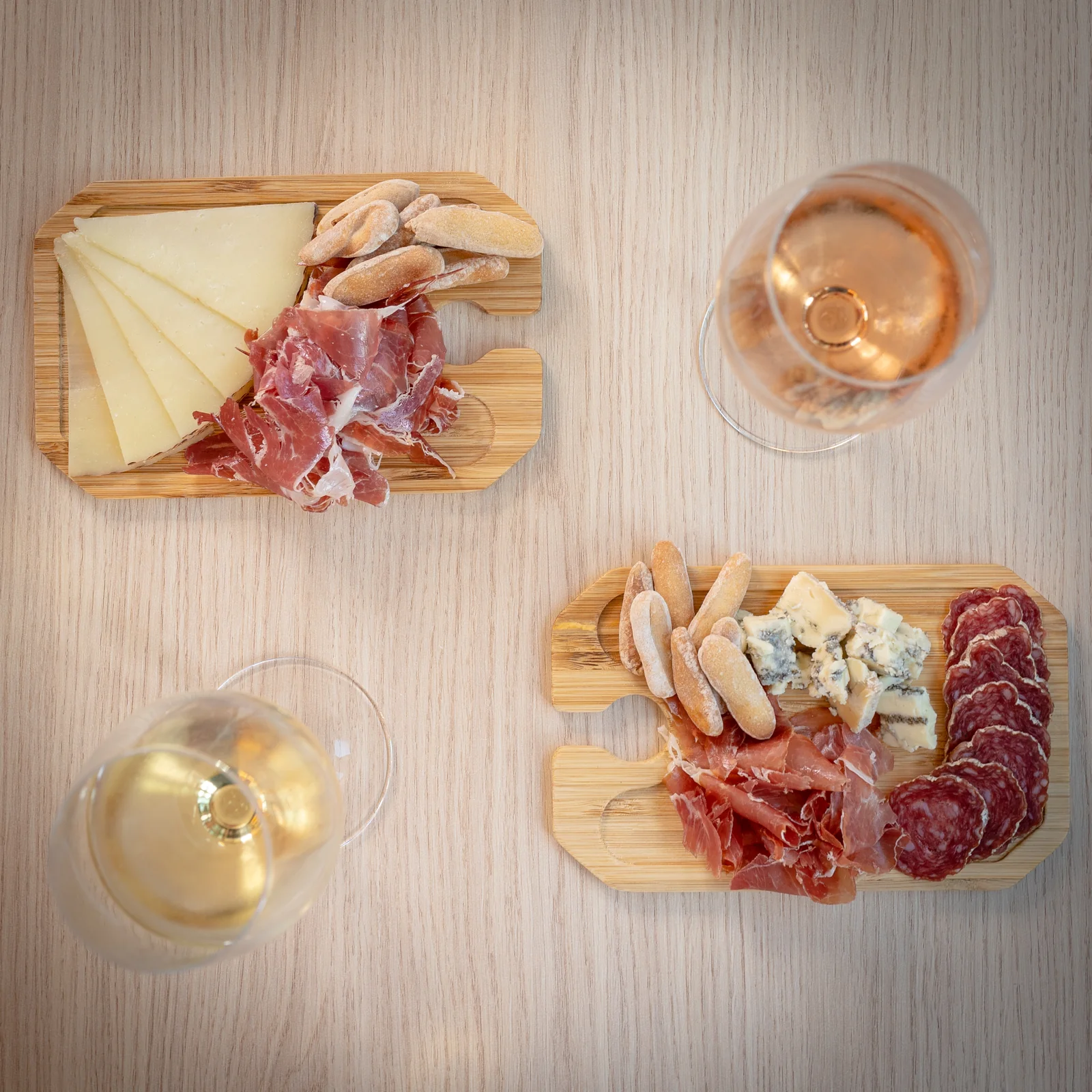 Two small boards of Spanish cheese and Iberian charcuterie with two glasses of wine