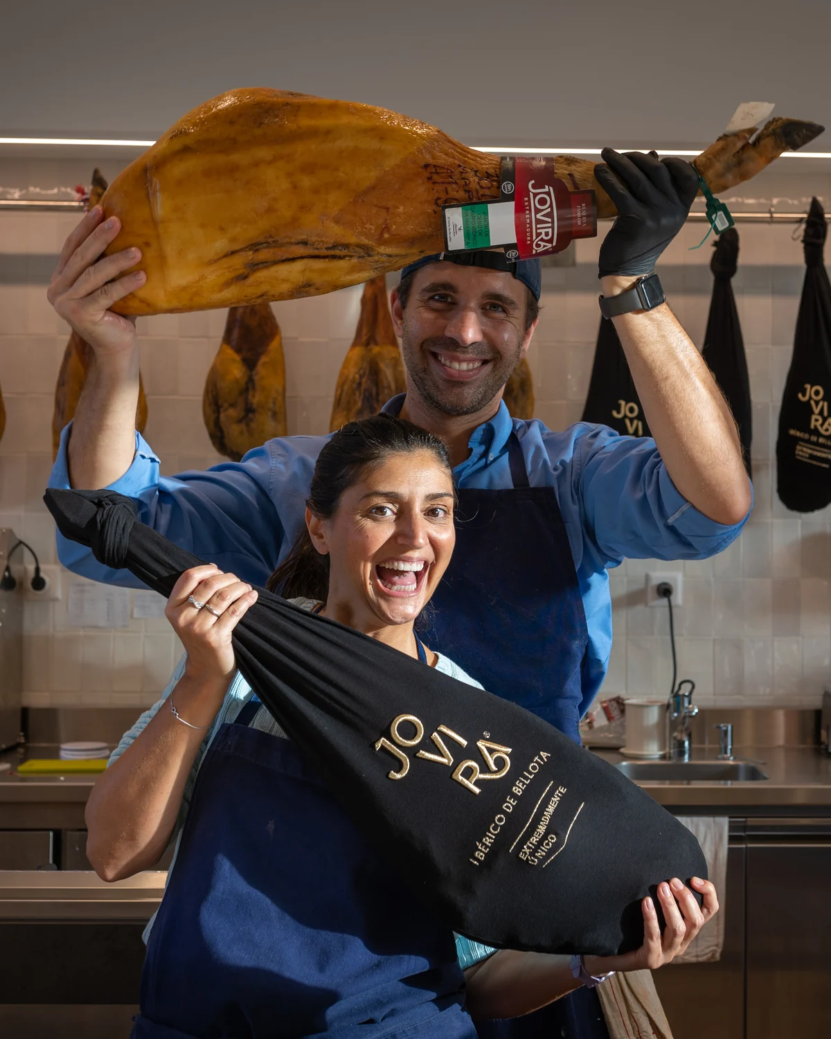 Ana Maria et Thomas tenant un jamón entier dans la boutique LA DULA à Genève