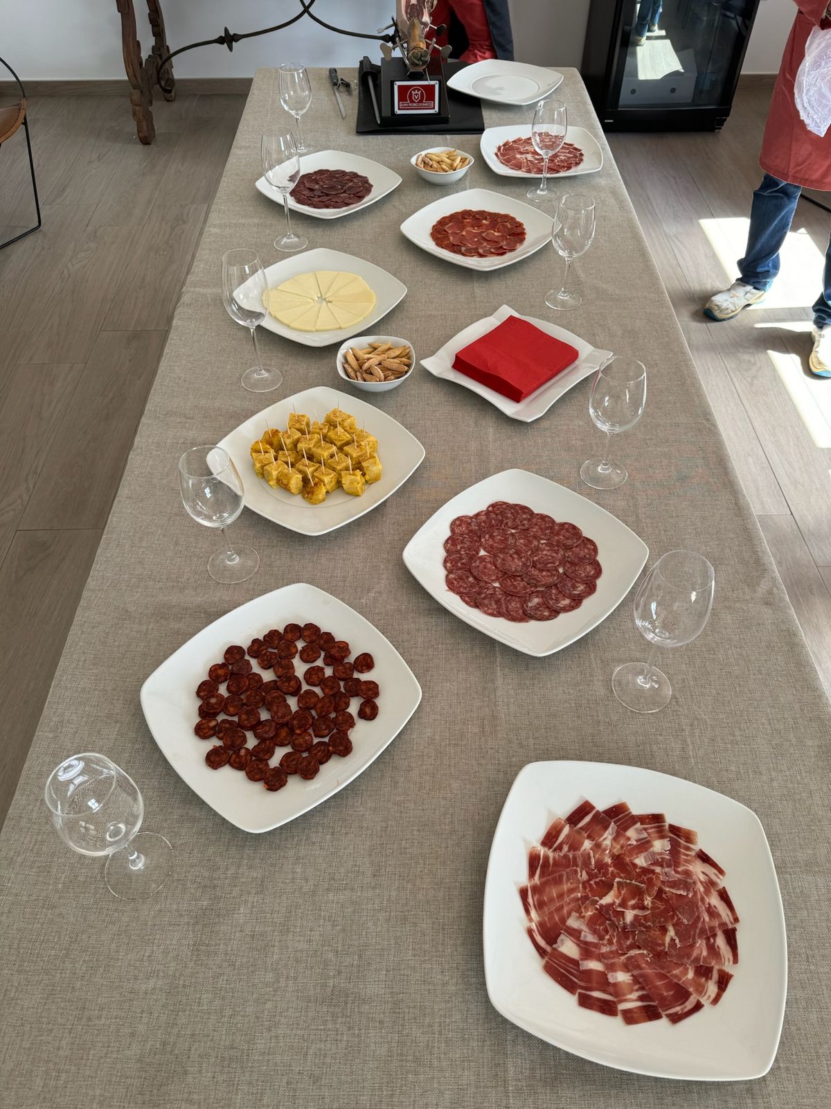 Mesa larga con platos de ibérico, queso y tortilla
